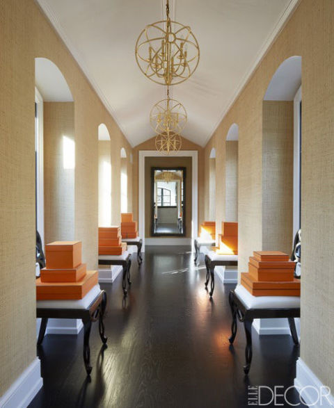 Chairs by Schumacher line an upstairs corridor; the light fixtures are custom made, and the wallcovering is by Élitis.
